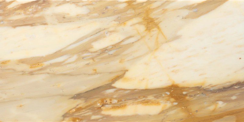 The deeper golden block, where the ground reads more ochre and the brown network is heavier, and the vein direction is read before the saw passes.